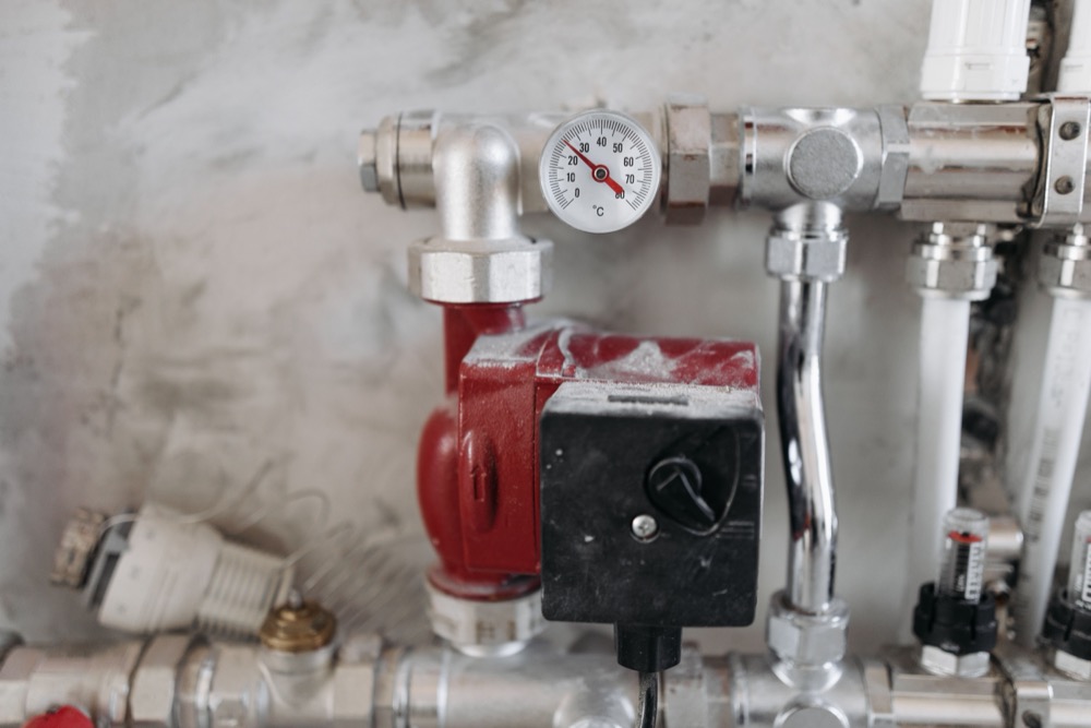 A boiler circulator pump and pressure gauge on a residential heating system