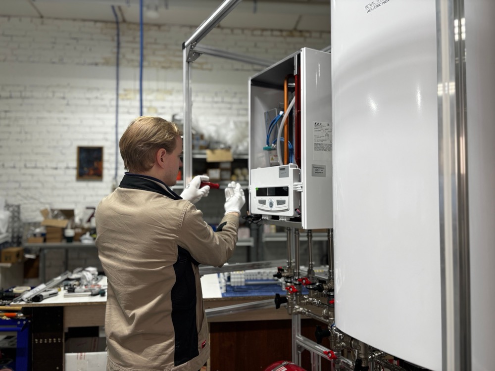 A technician servicing a wall-mounted residential boiler